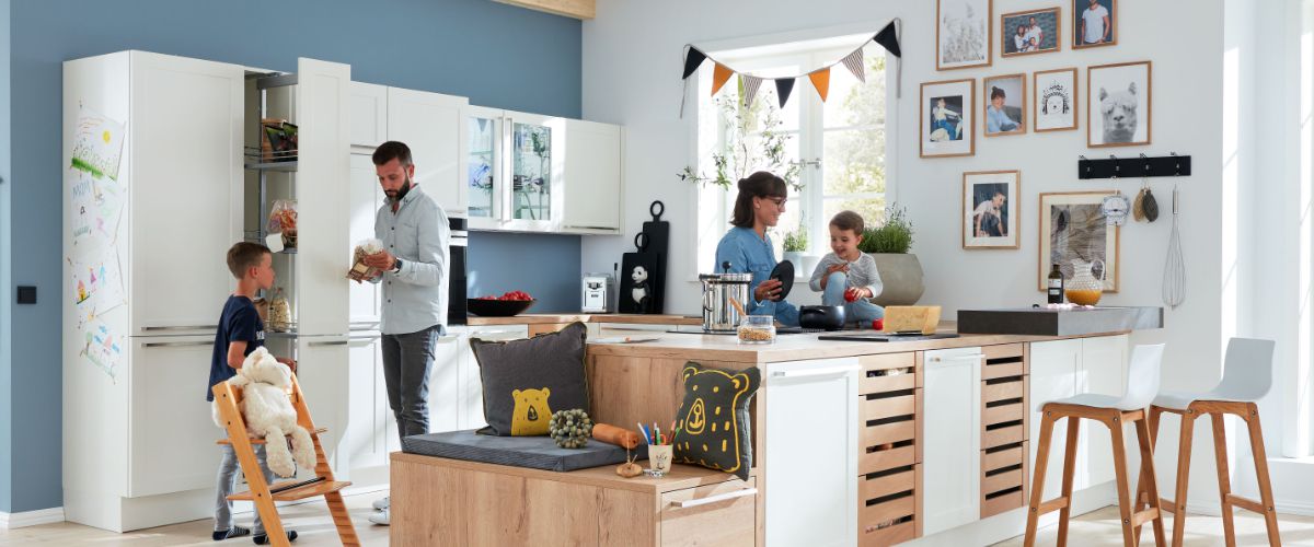 Moderne Familienküche mit versteckter Speisekammer, vier Personen, viel Stauraum und dekorativen Kissen mit Bärmotiv.